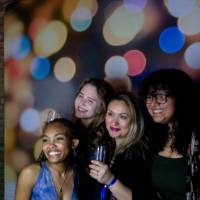 Grads smile at photo booth backdrop with champagne